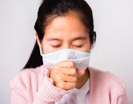 Asian woman wearing surgical protection cloth face mask hygiene against coronavirus and her sneeze hand close mouth, studio shot isolated on white background with copy space, COVID-19 concept