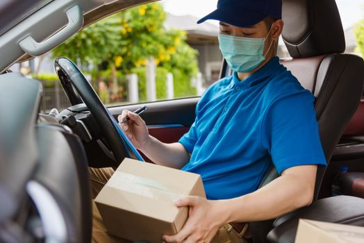 Asian delivery courier young man driver inside the van car with parcel post boxes checking amount he protective face mask, under curfew quarantine pandemic coronavirus COVID-19