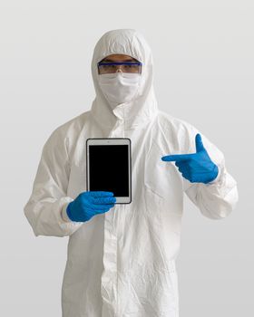 Epidemiological researchers in virus protective clothing holding blank screen tablet computer.
