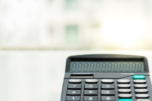 Calculator on the white table near window, closeup sideview isolated