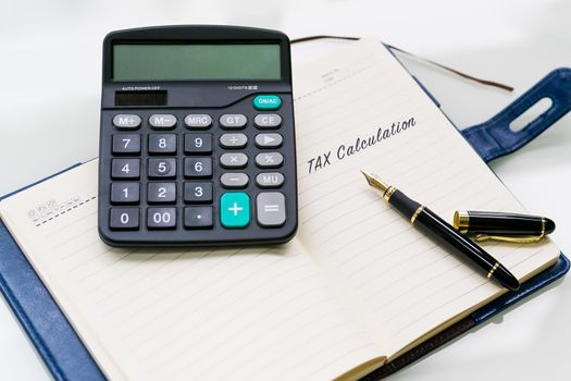 pen, calculator and notebook with TAX Calculation word on the white table backgrounds