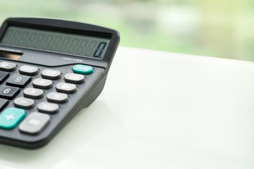 Calculator on the white table near window, closeup sideview isolated