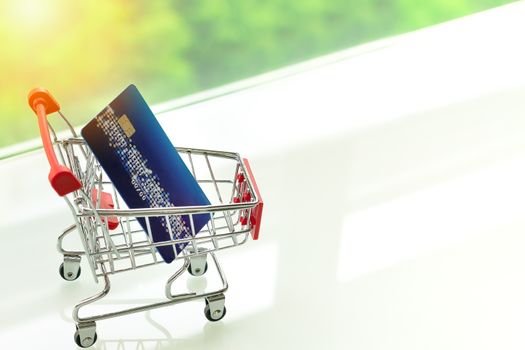 credit card on shopping cart trolley on white table with green backgrounds