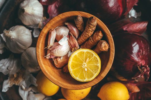 Bowl with turmeric, garlic, lemon with garlic, lemon and onion in the background