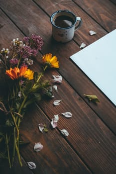Blank paper with spring flowers with a small white cup of coffee on a rustic wooden table