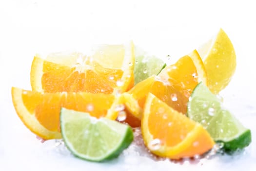 Various types of citrus fruit in splash of water drops