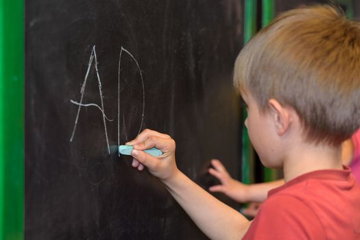 Little boy learn to write on a blackboard in the kindergarten or the classroom