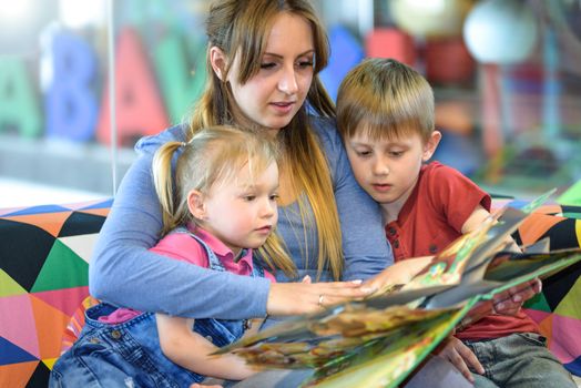 Portrait of pretty young women reading fairy tales with two children in the shopping center