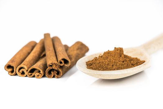 Cinnamon sticks and wooden spoon with ground cinnamon powder on white background