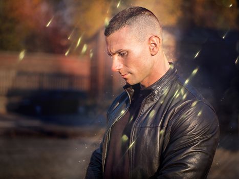 One handsome young man in urban setting in European city, standing, wearing black leather jacket and jeans