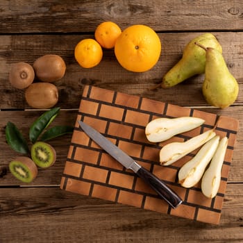 Juicy whole and sliced fruit with a knife on a wooden cutting board