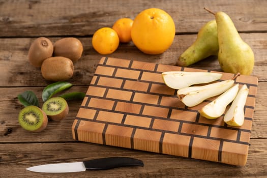 Juicy whole and sliced fruit with a knife on a wooden cutting board