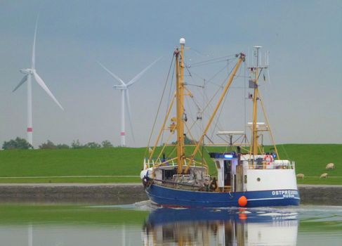 Photo of a ship and a meadow with wind wheel
