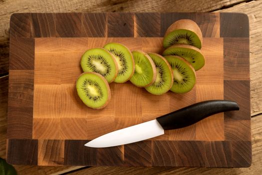 Juicy green kiwi sliced on wooden carving board