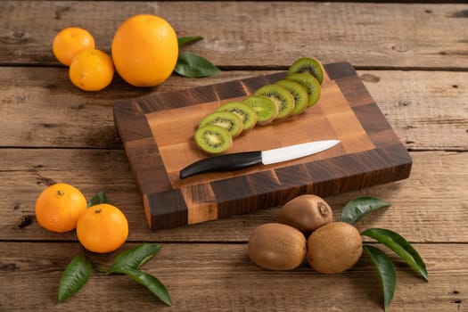 Juicy whole and sliced fruit with a knife on a wooden cutting board