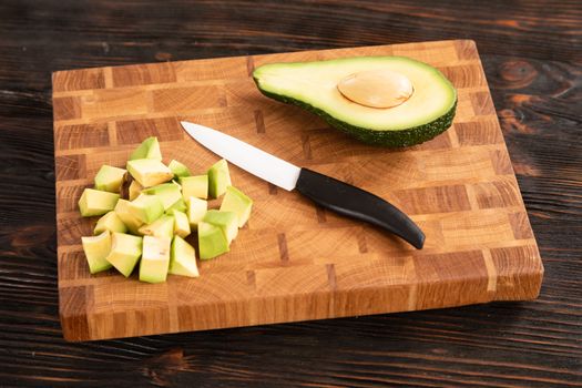 Avocado sliced with cube using knife on wooden cutting board