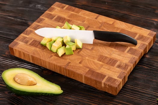 Avocado sliced with cube using knife on wooden cutting board