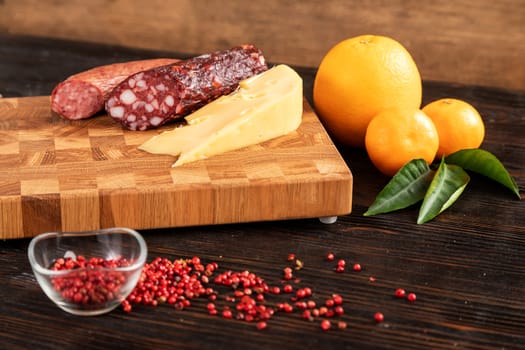 Sausage, cheese and fruit on wooden cutting board