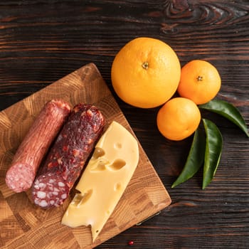 Sausage, cheese and fruit on wooden cutting board