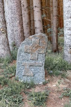 Old boundary marker on rock at forest. On stone carved symbol of cross and ax. Czech Republic