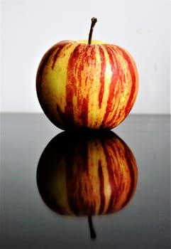 Photo of an apple reflecting on a glass table