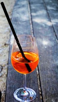 Orange Aperol Spritz drink with straw on wooden table
