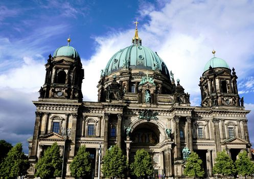 Berliner Dom behind trees with blue sky and clouds