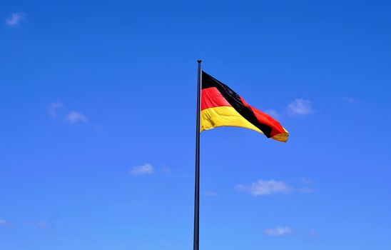 German flag waving in wind in front of blue sky