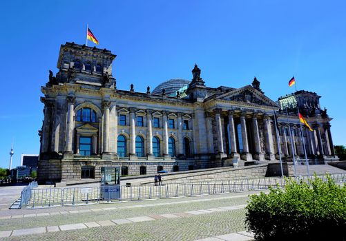 Berlin Reichstag building with German flags and blue sky