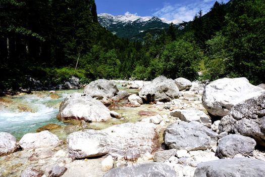 Rocks in Isonzo river near Trenta, Slovenia with Julian alps in background