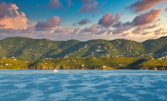 A tropical green island across blue water of a calm sea