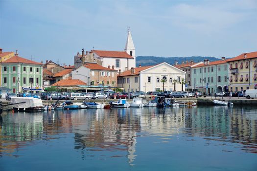 Small square with church and cars at the port of Izola, Slovenia