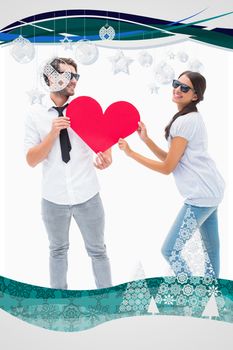 Hipster couple smiling at camera holding a heart against christmas frame