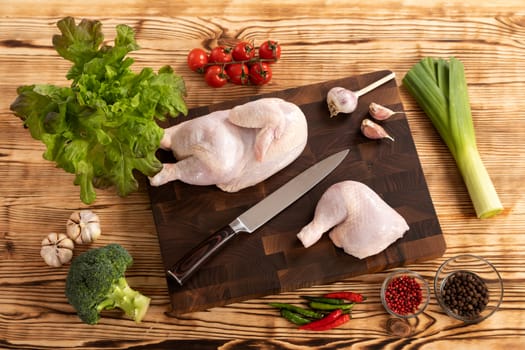 Raw chicken and vegetables for cooking lie on a wooden cutting board