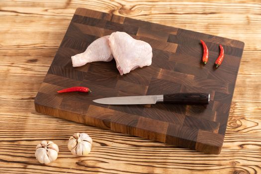 Raw chicken and vegetables for cooking lie on a wooden cutting board