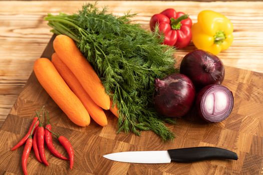 Raw chicken and vegetables for cooking lie on a wooden cutting board