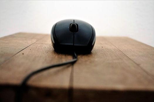 Black computer mouse and wire on wooden table