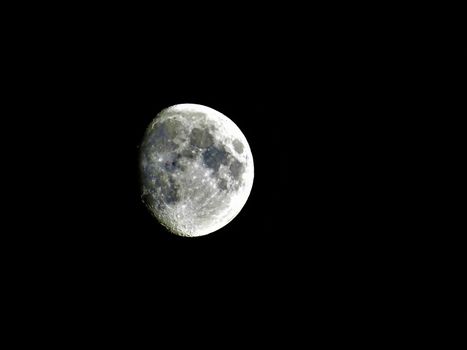 Three quarter moon shining on the night sky