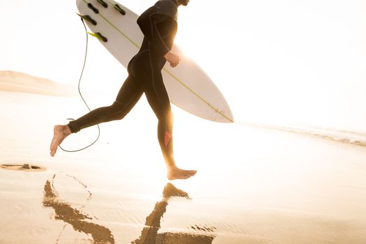 A surfer with his surfboard running to the waves