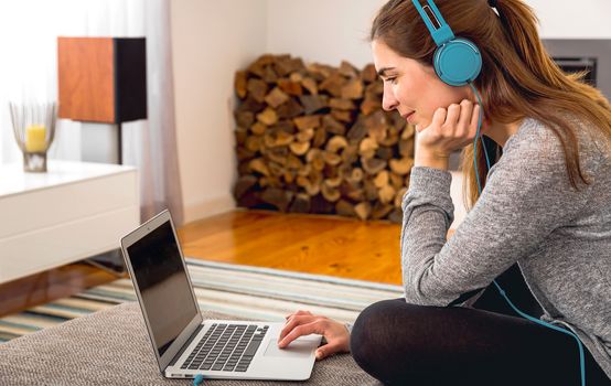 Beautiful woman working at home with a laptop while listen music