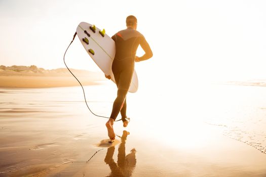 A surfer with his surfboard running to the waves