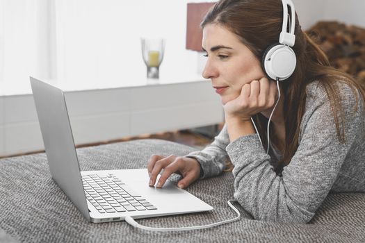 Beautiful woman working at home with a laptop while listen music