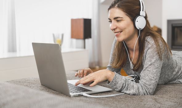 Beautiful woman working at home with a laptop while listen music