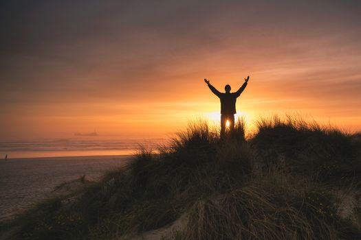 Silhouette man on the sand dunes at sunset