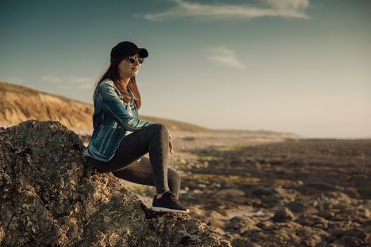Beuutoful woman alone in the beach sitting on the rocks