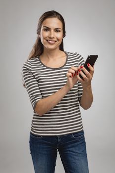 Beautiful happy young woman sendind a text message to someone