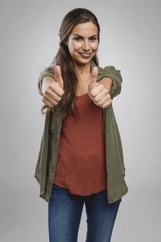 Beautiful woman over a gray background with thumbs up