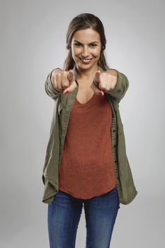 Beautiful happy woman looking and pointing with both arms to the camera