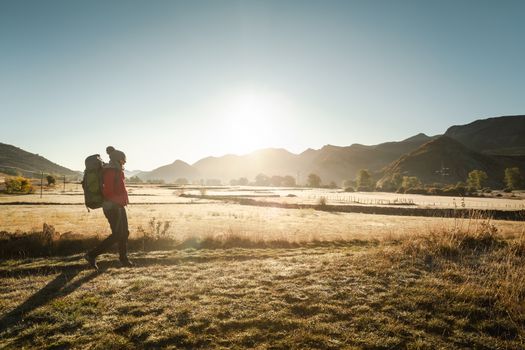 Shot of a woman walking with a backpack at sunrise