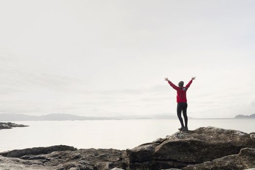 Woman with arms raised  enjoying the beautiful morning view of the coast